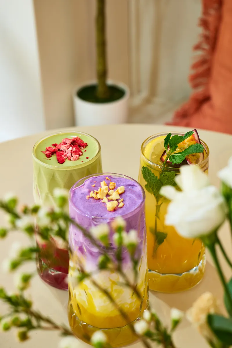 Matcha- und Ube-Drinks im hohen Glas zwischen Blumen